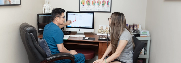 Acupuncturist Flower Mound TX Choong Shim With Patient In Office Dr. Choong Shim consulting with a patient in his office.