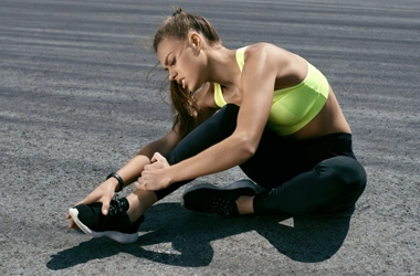 A person holding their foot while sitting on a track.
