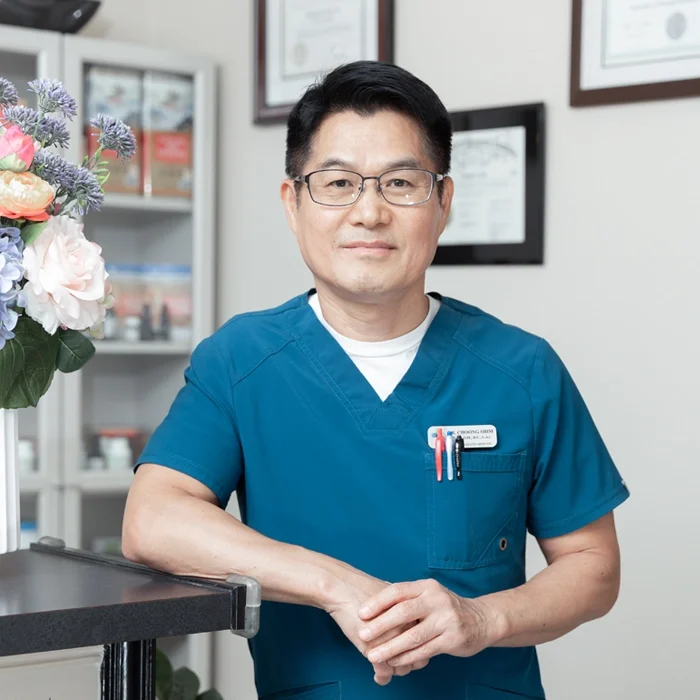 Acupuncturist Flower Mound TX Choong Shim HP Dr. Choong Shim smiling next to a vase of flowers.